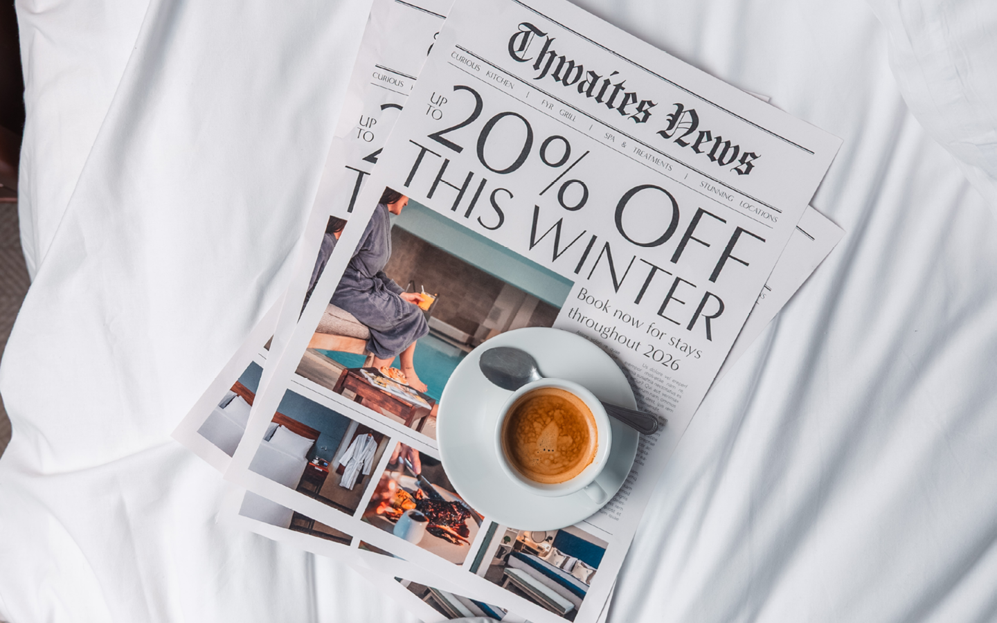 Newspaper and coffee on hotel bed that reads "Up to 20% off this winter"